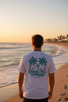 Man on Florida beach wearing white Under the Palms Teal tee, back view