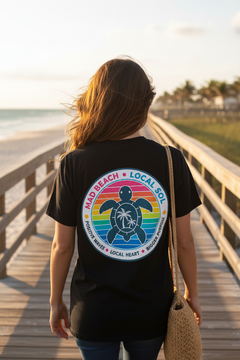 Back of Local Sol Badge Tee on woman walking Florida beach boardwalk